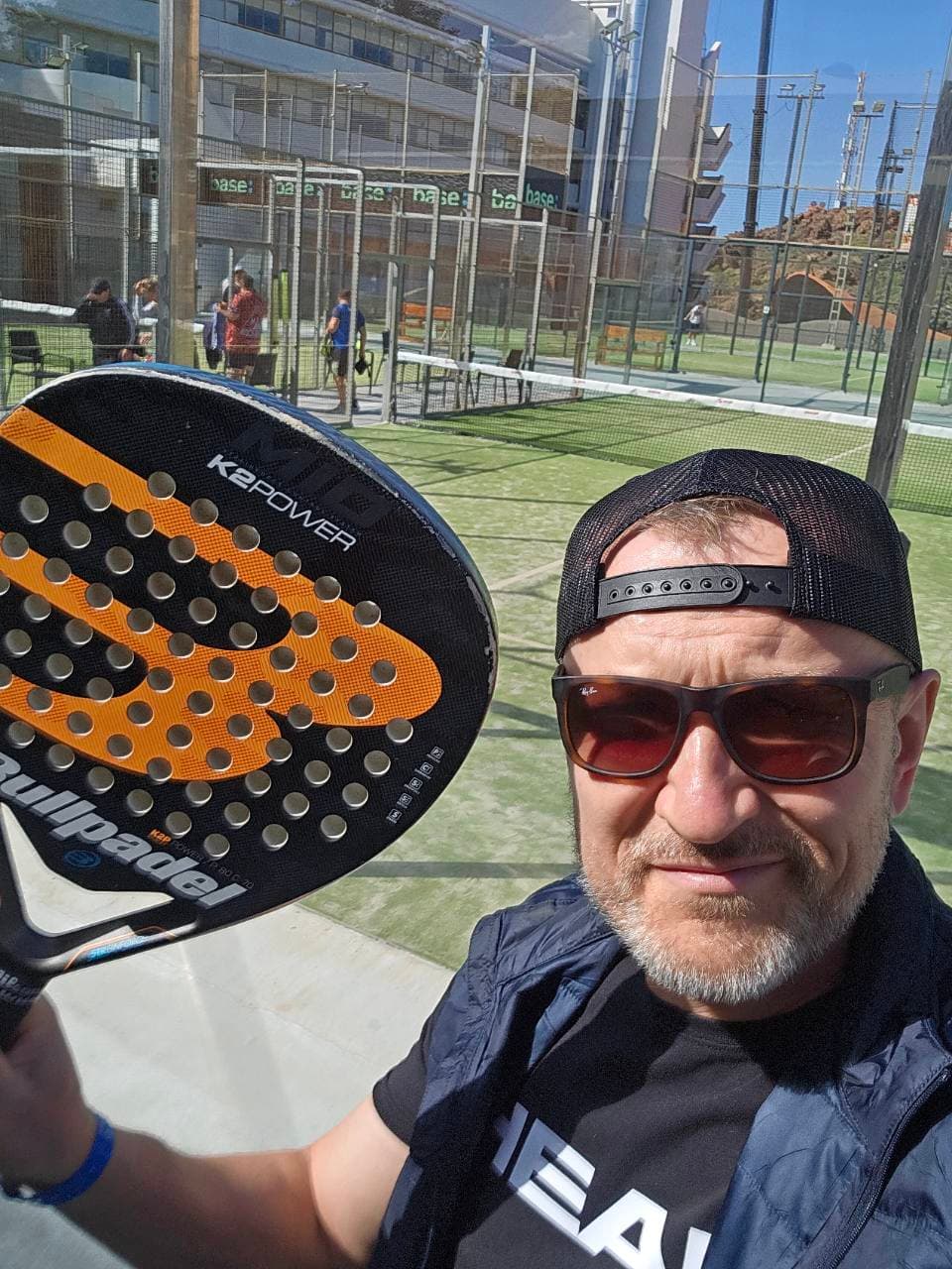 Padel coach taking a selfie with a racket on an outdoor court